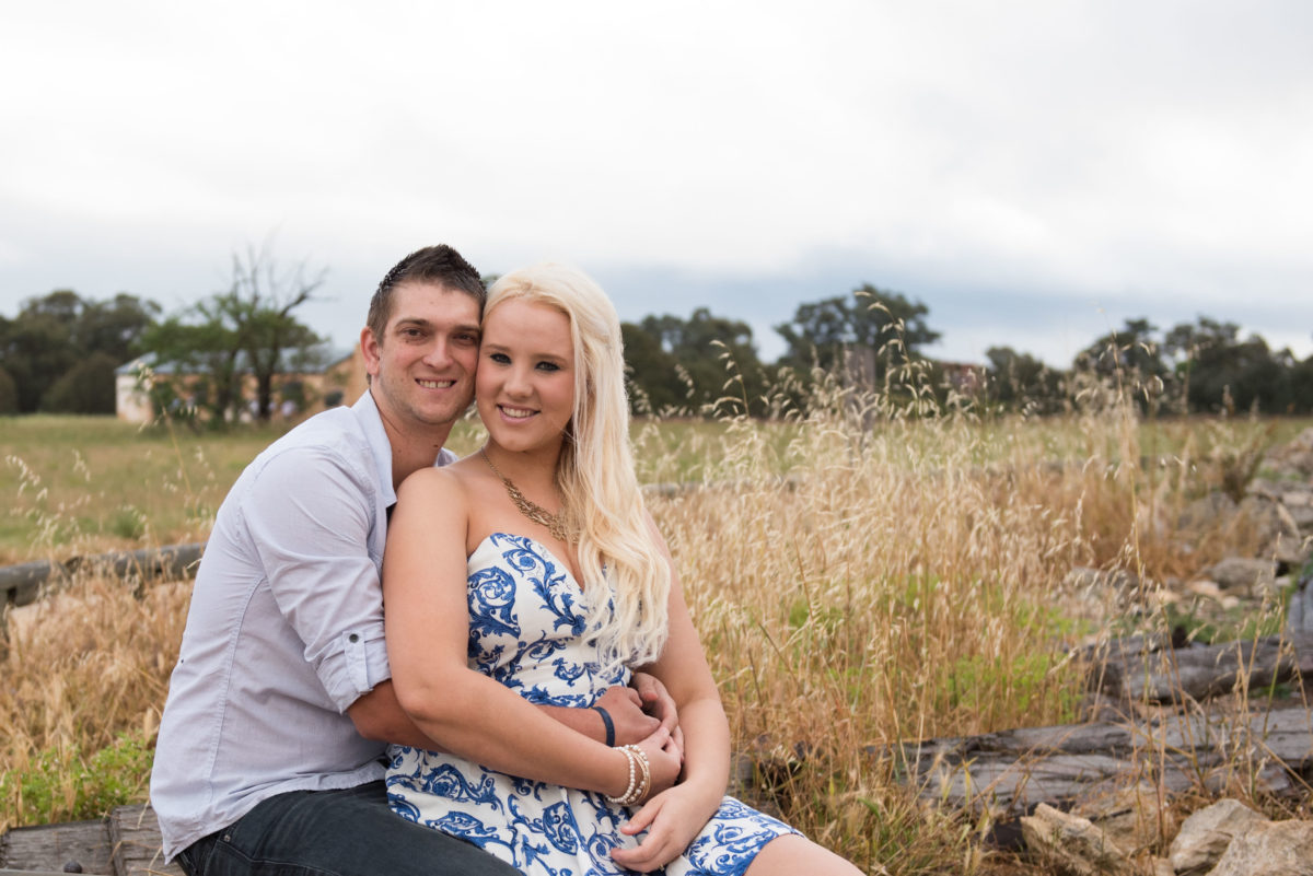 Engaged couple cuddling up on a log