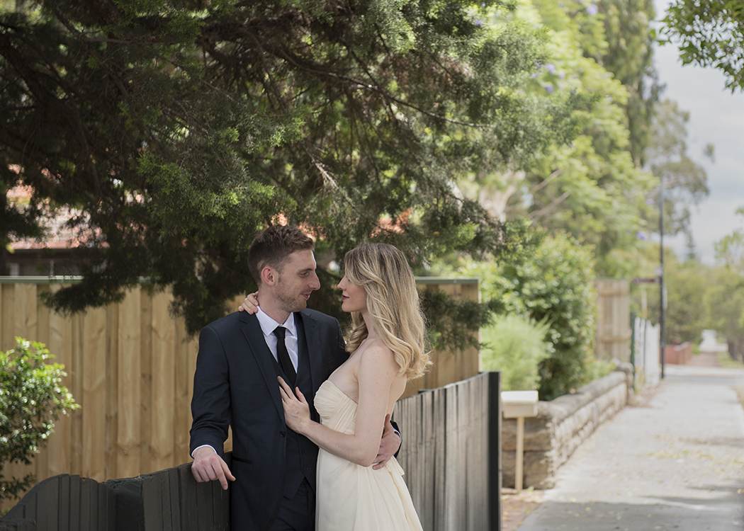 Bride and Groom leaning against suburban fence