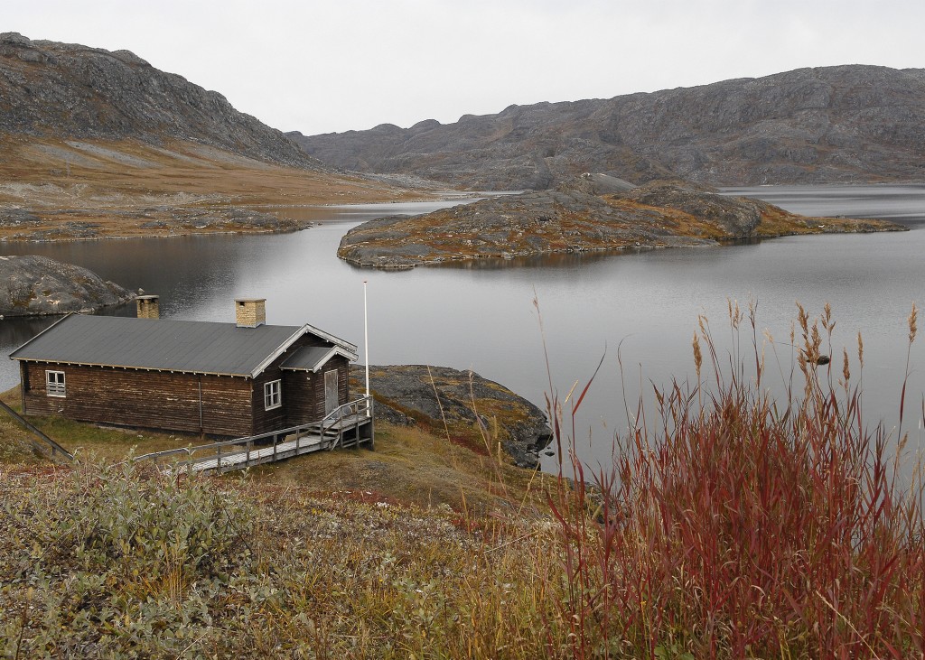 Wooden house next to a perfectly still lake in Qaqortoq, Greenland