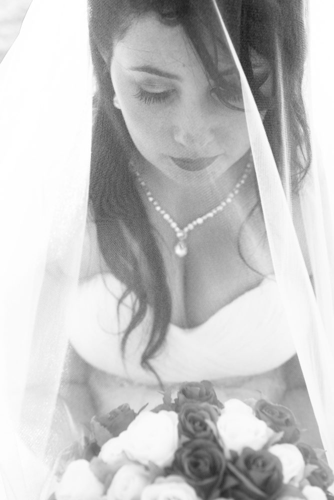 Black and white close up shot of bride through the veil. bridal jewellery. long eyelashes