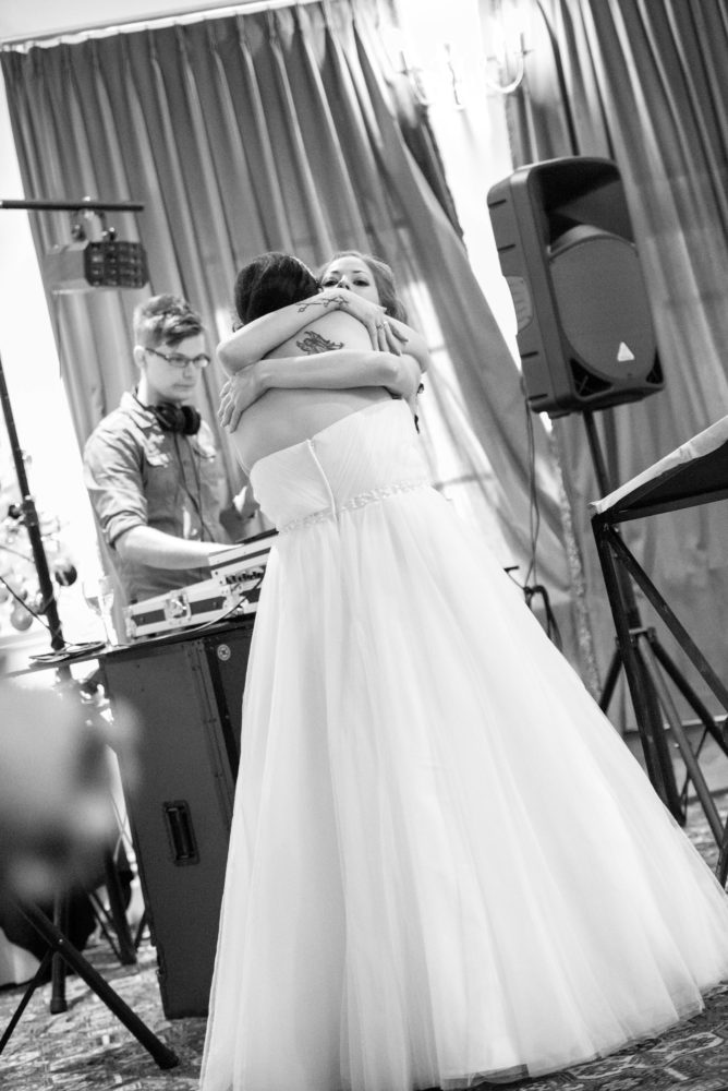 Black and white photo of bride hugging her sister during the wedding reception. Weddings and tattoos