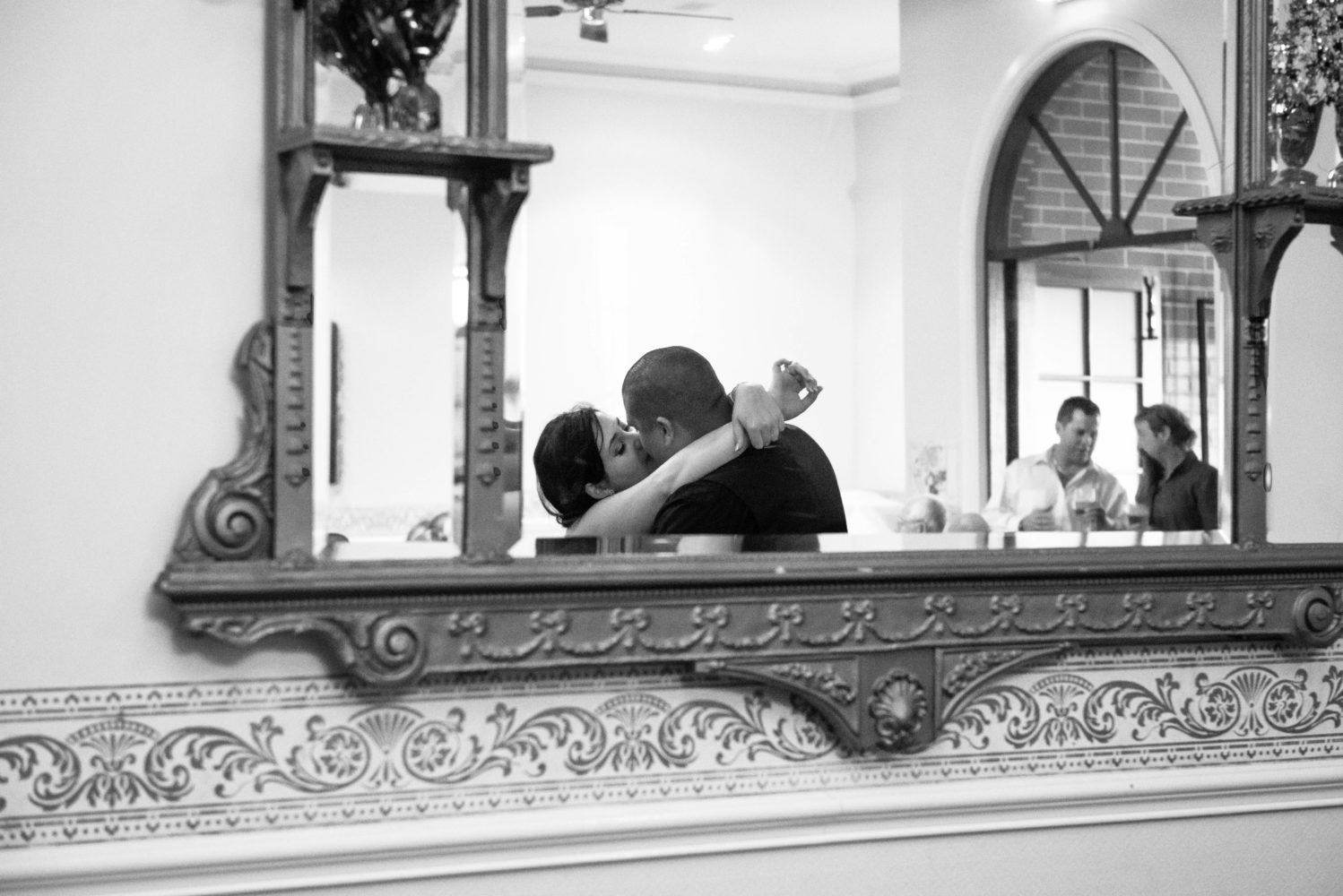 Black and white photo of bride and groom kissing reflected in antique mirror