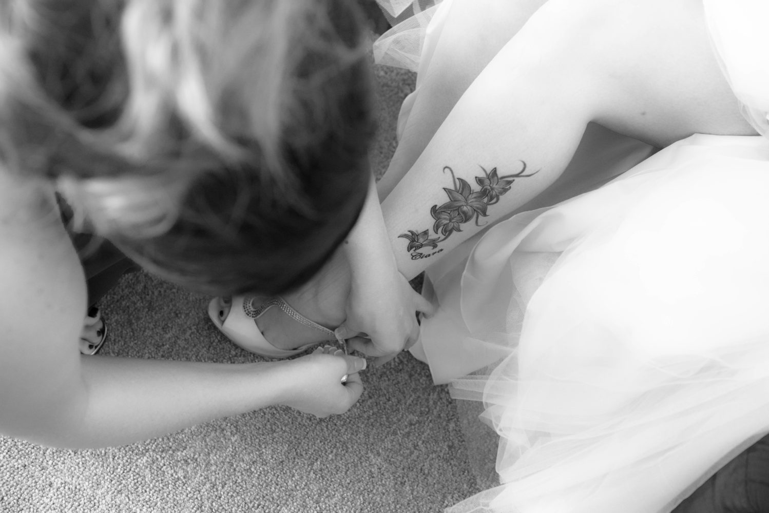 Bride getting ready detail of putting wedding shoes on. Tattoo on calf. Black and white photo. Wedding and tattoos