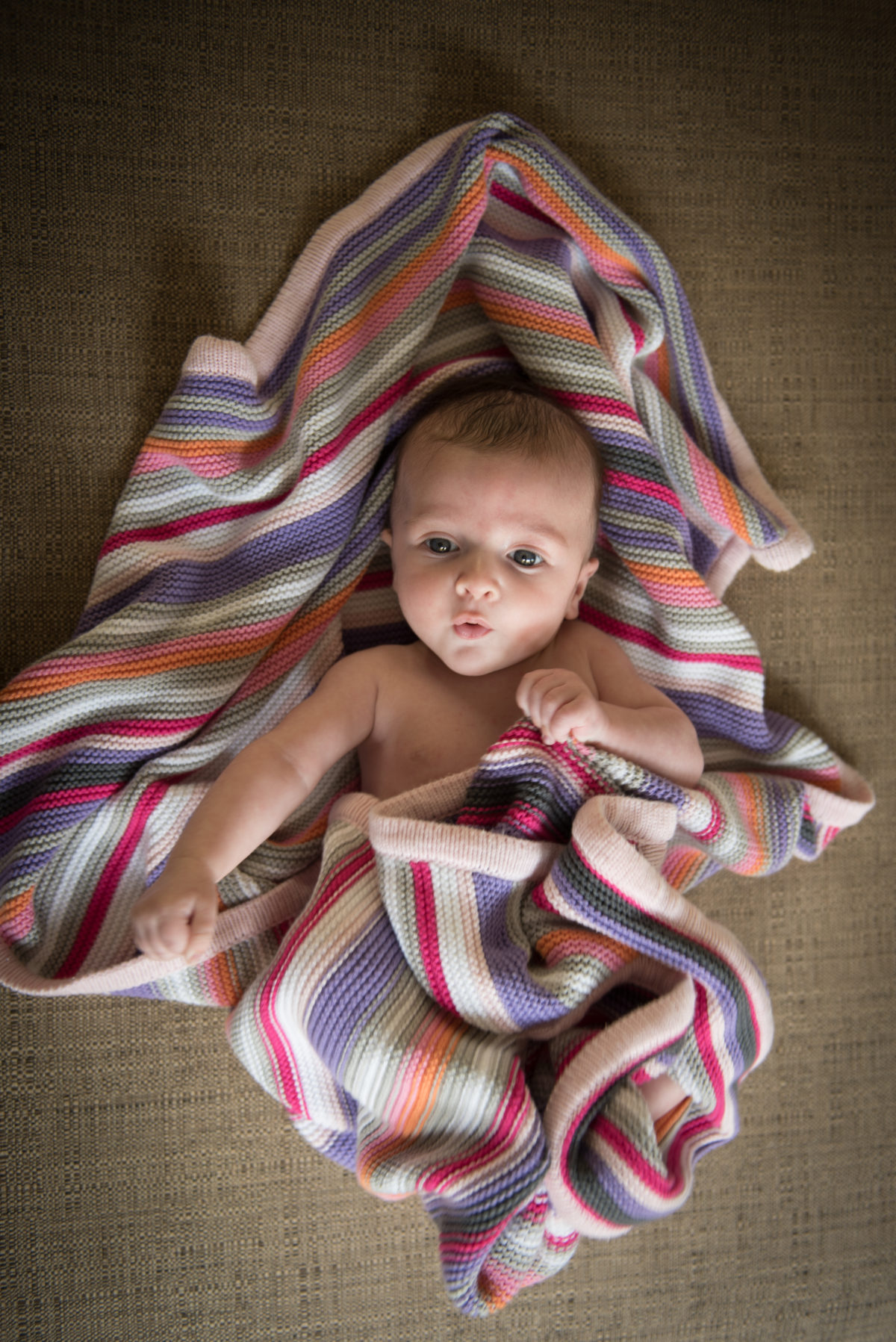 Photo of baby in a stripey blanket from above