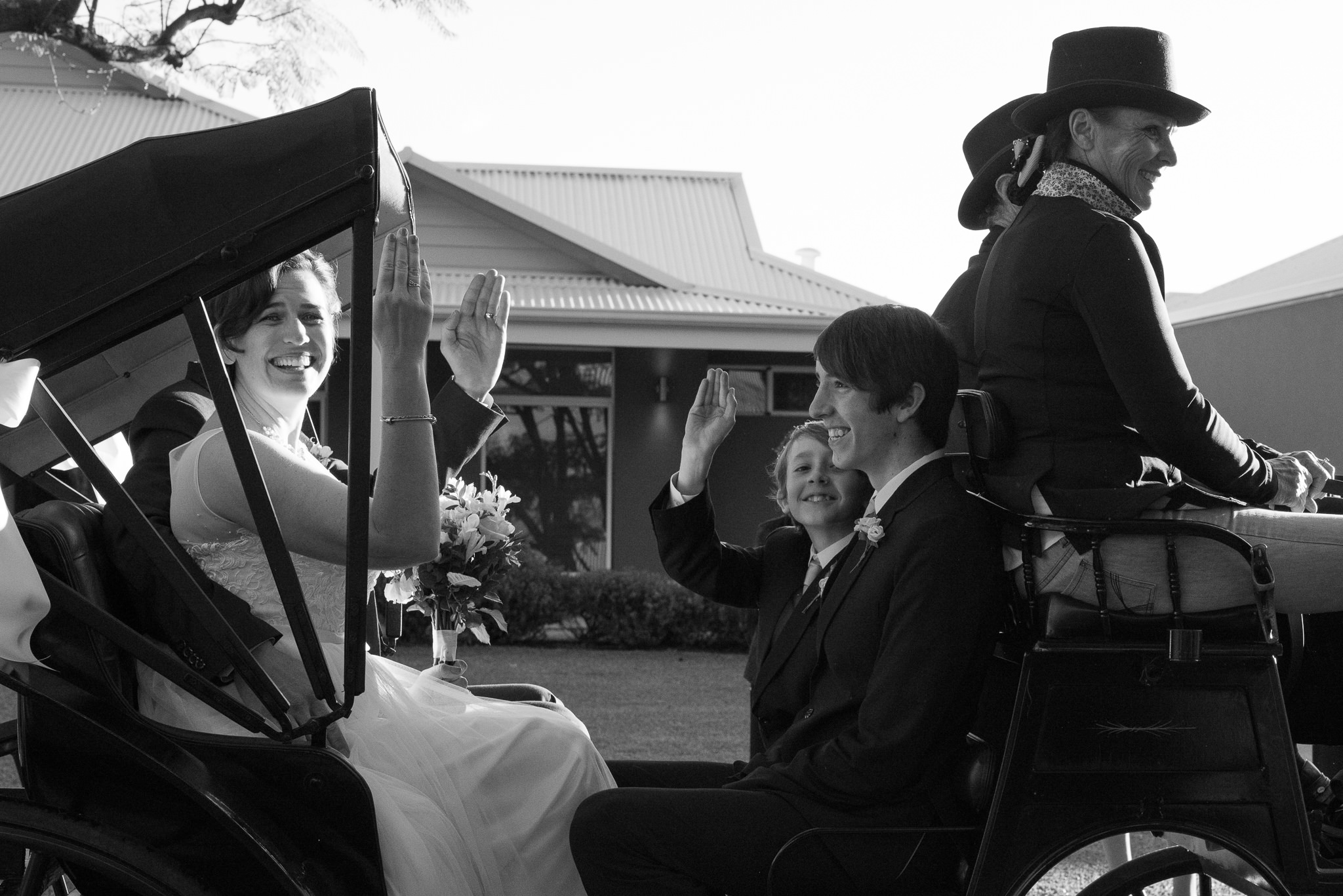 bride waves as they roll by in their horse and carriage