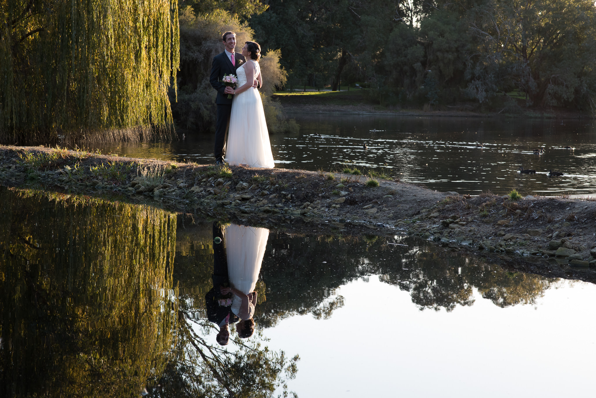 bride and groom standing on rocks with reflection