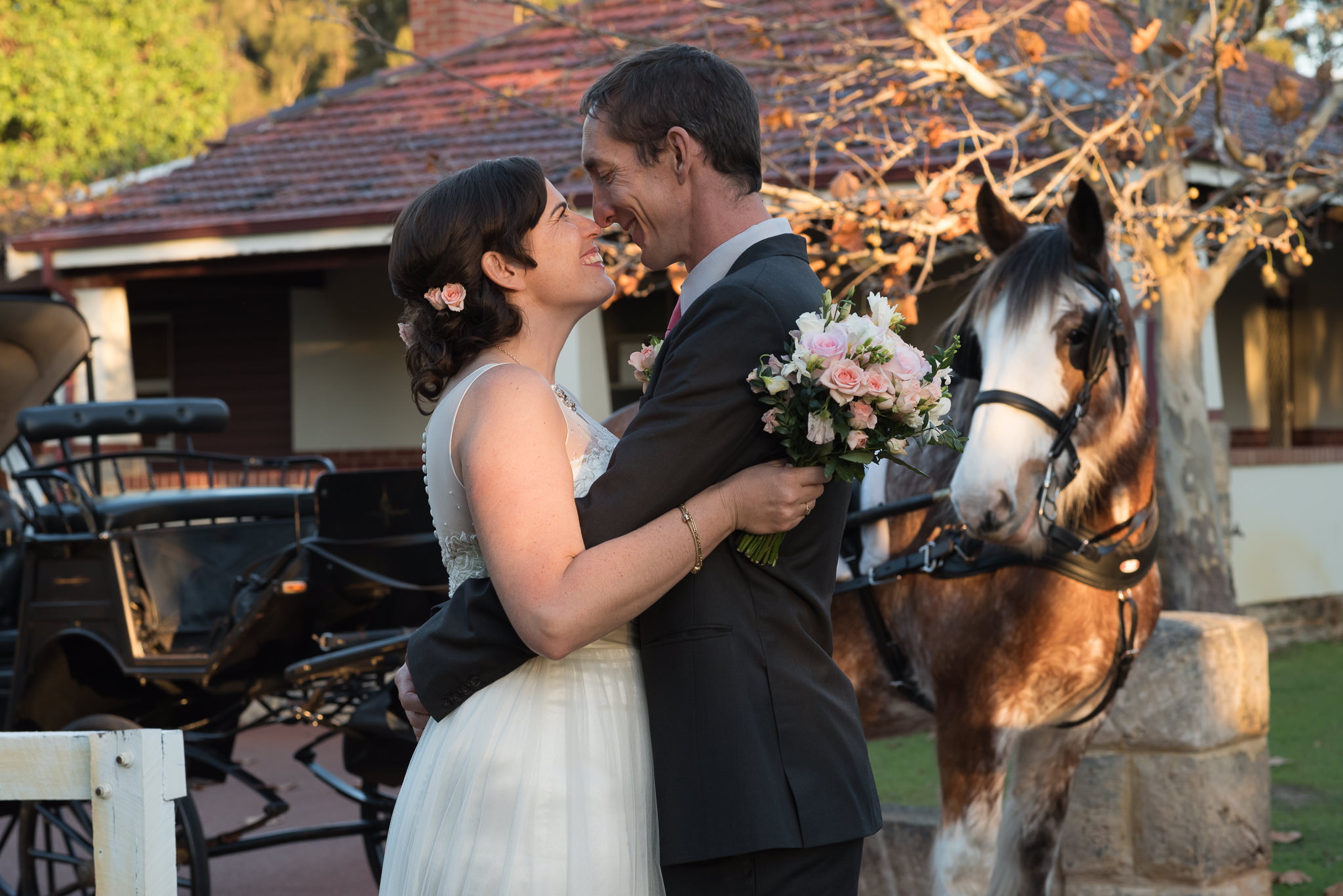 bride and grooms mile at each other with their horse looking on