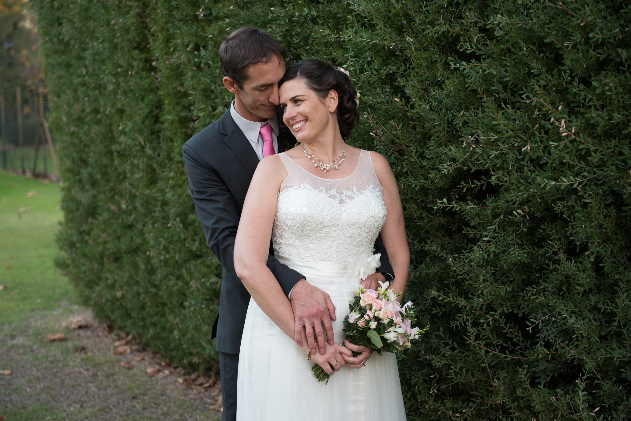 Bride and groom portrait next to hedge