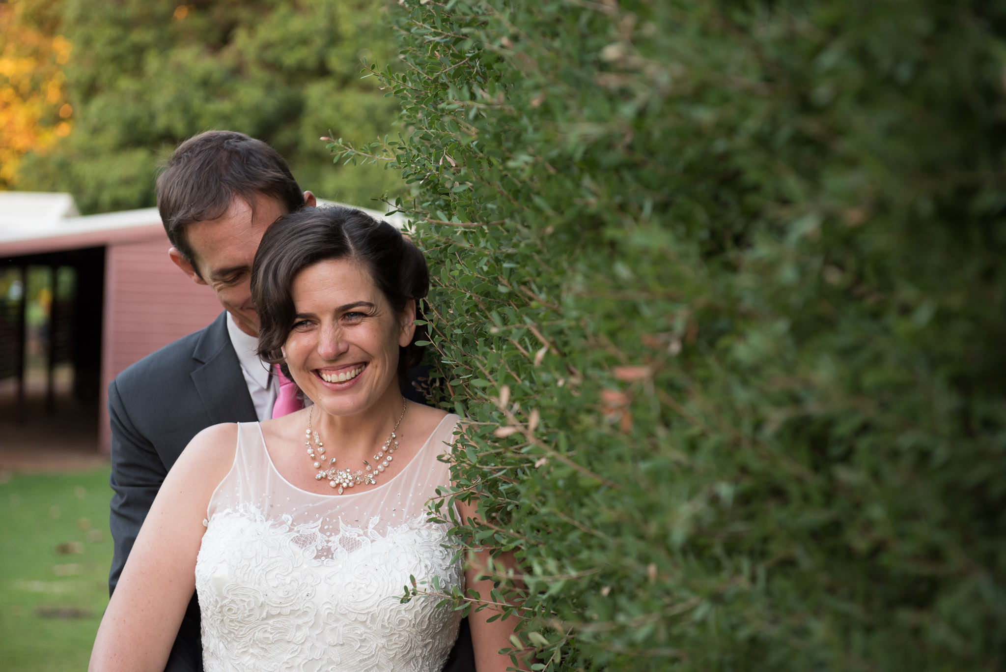 Bride and groom next to hedge