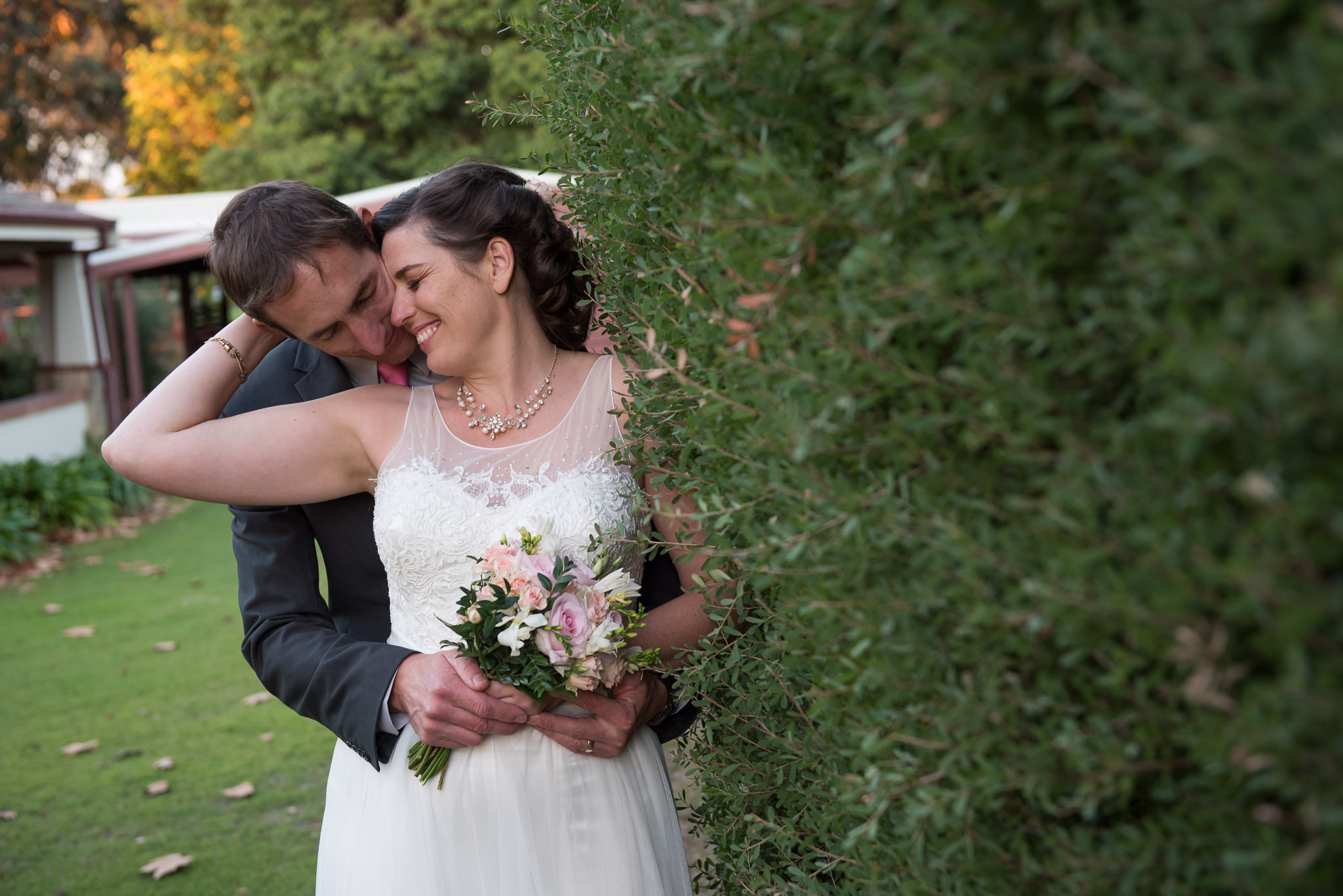 Bride and groom next to hedge