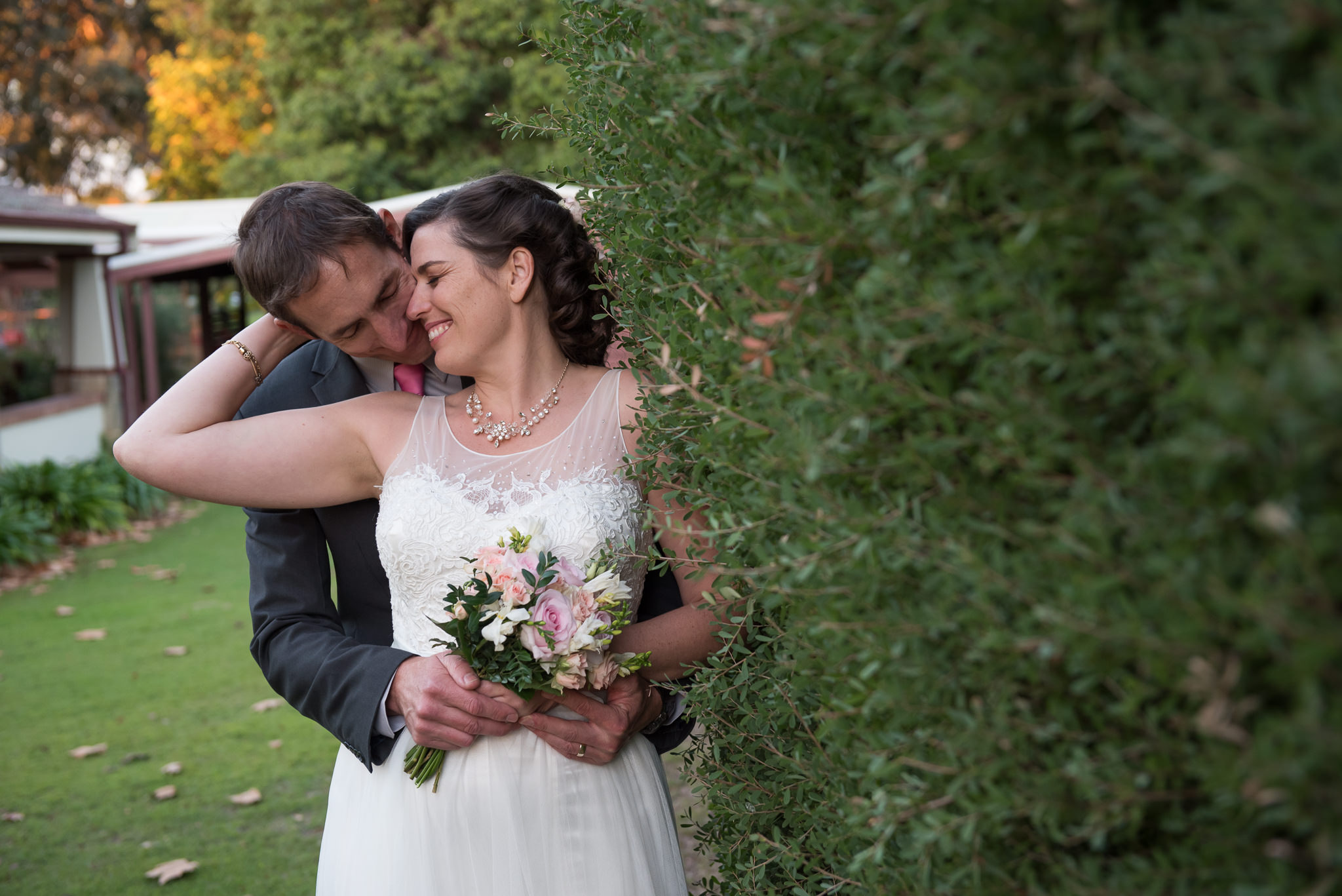 Bride and groom next to hedge