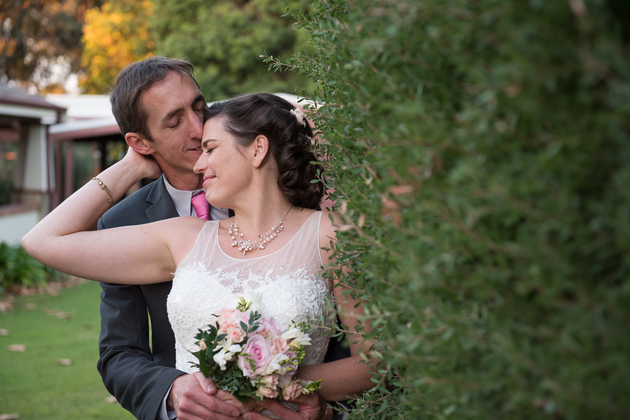 Bride and groom next to hedge