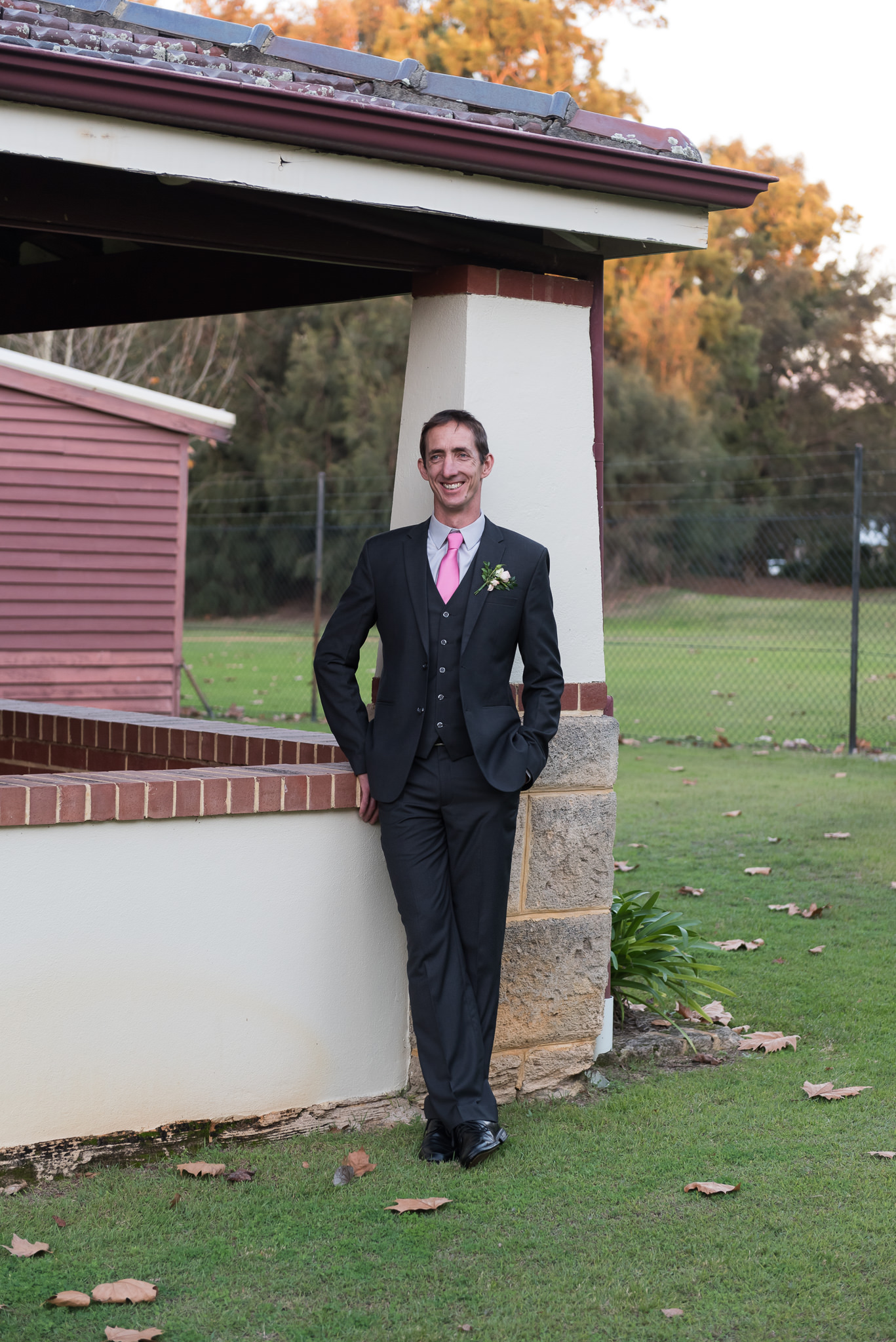 Groom resting against house