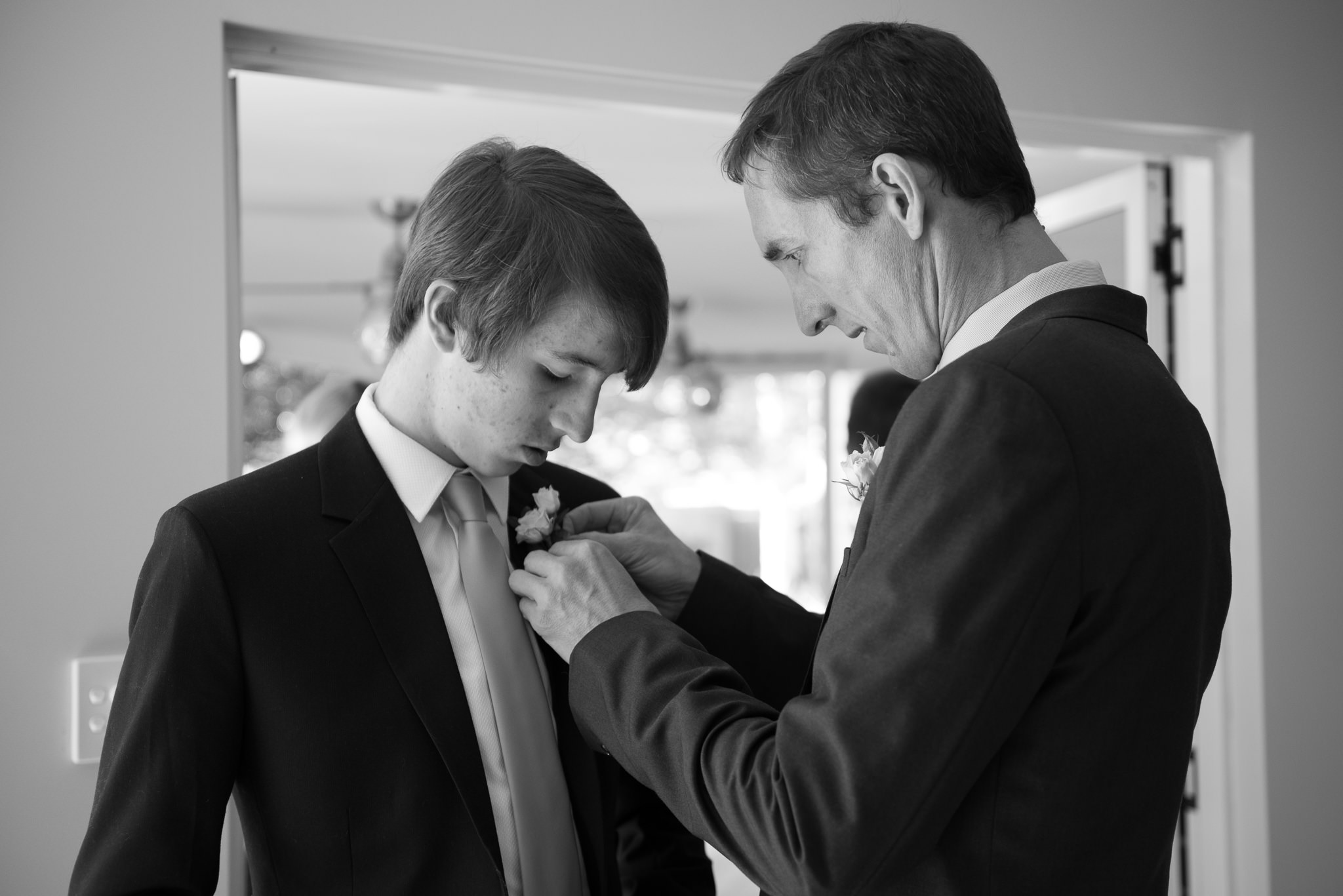 groom fixes his son's buttonhole