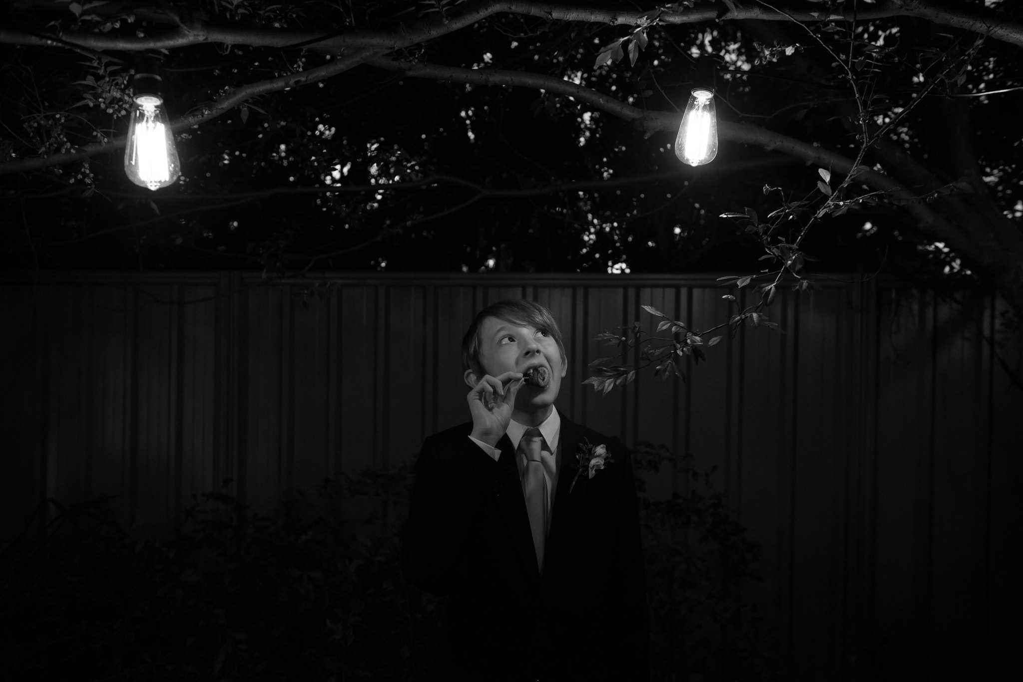 Groom's son looking at lightbulb at reception eating chicken