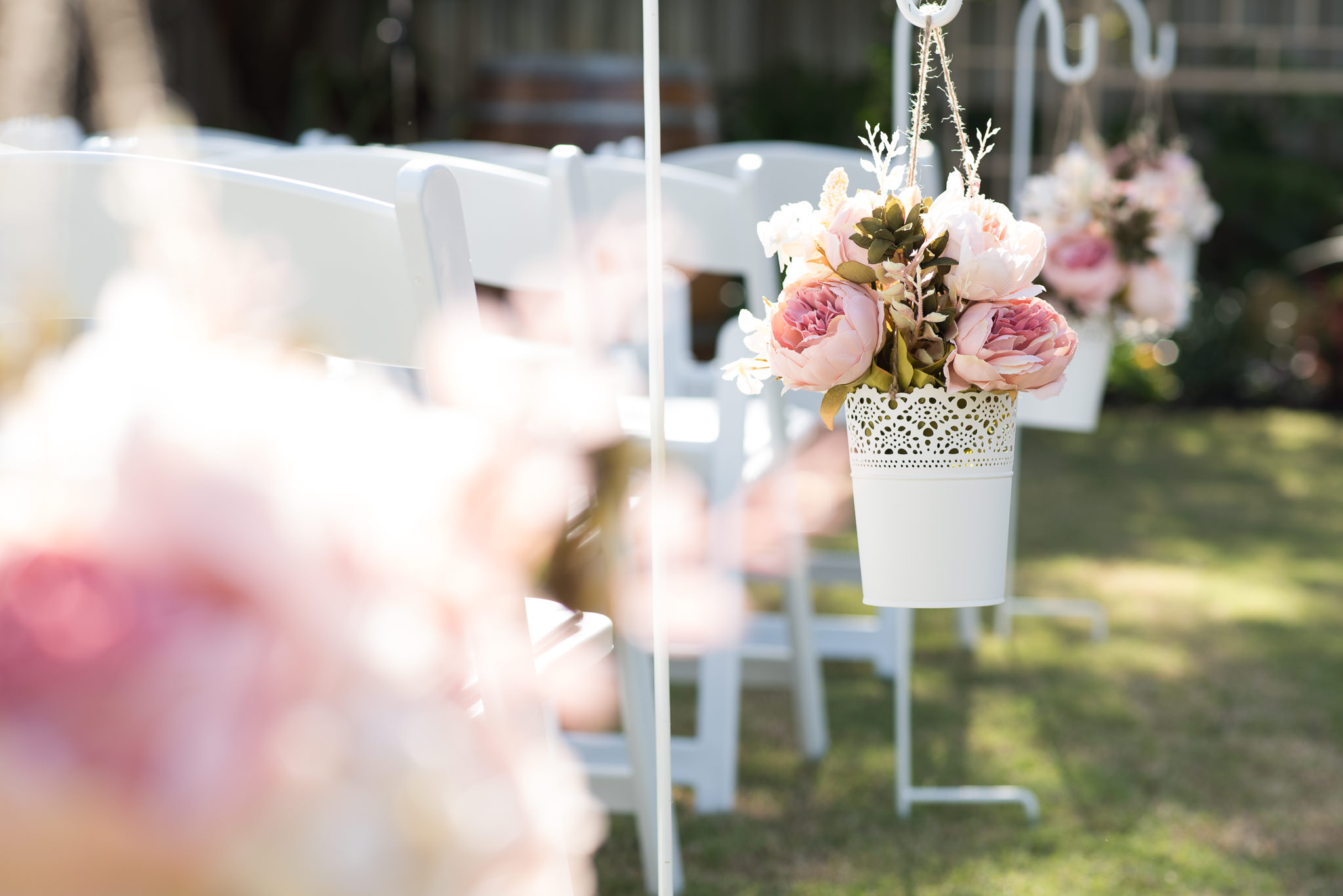 row of pew decorations, flowers in a white bucket