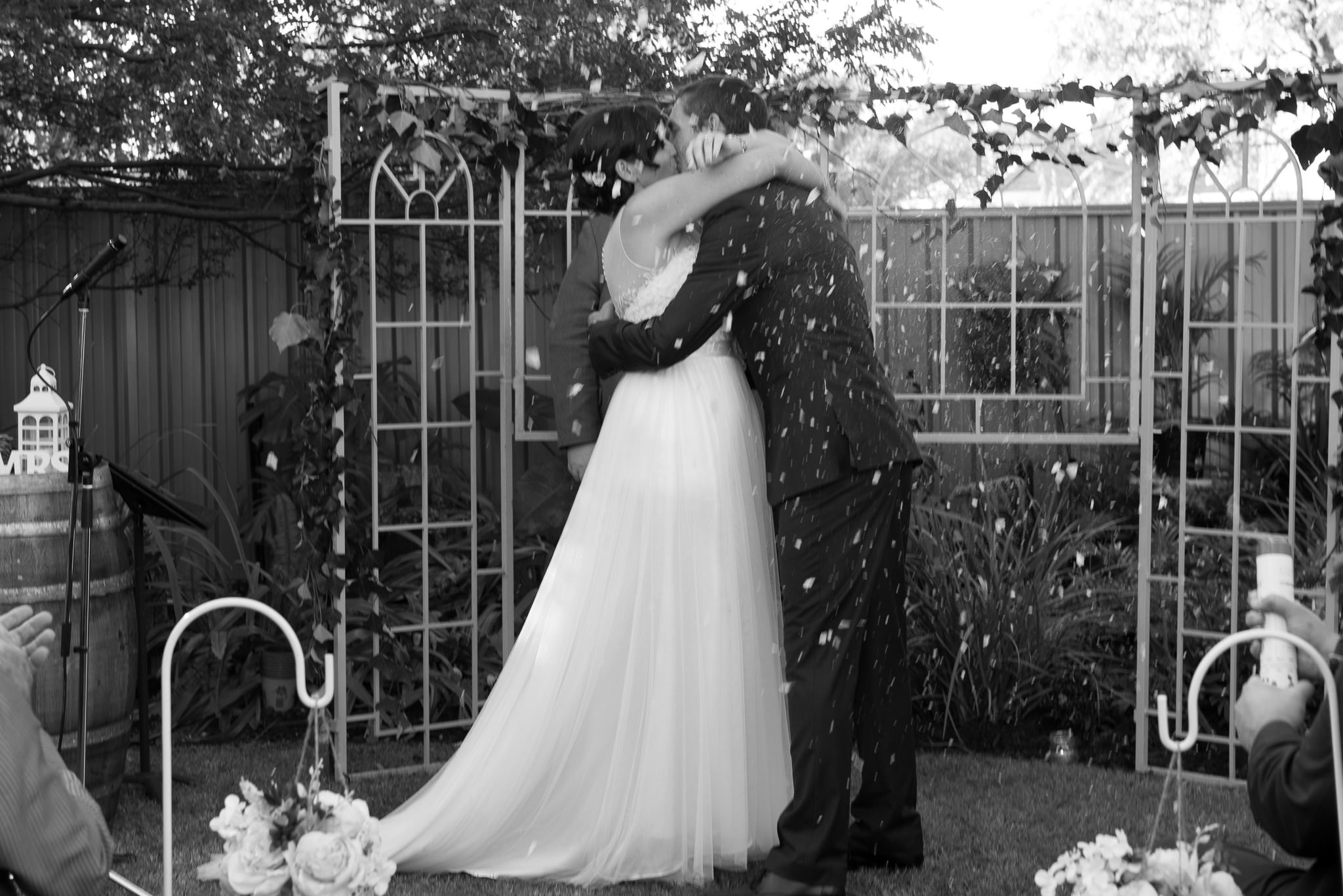 confetti cannon fires over wedding couple kissing