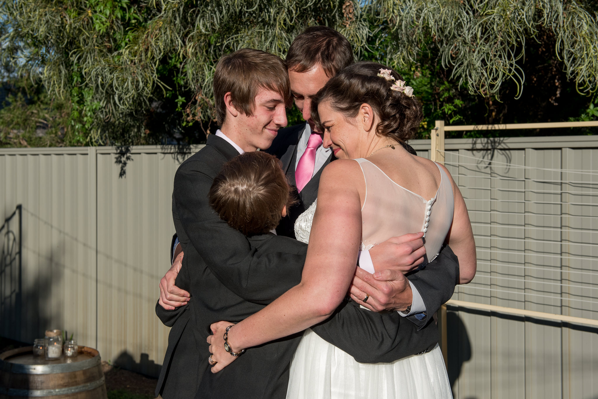 bride and groom and sons hug after the wedding ceremony