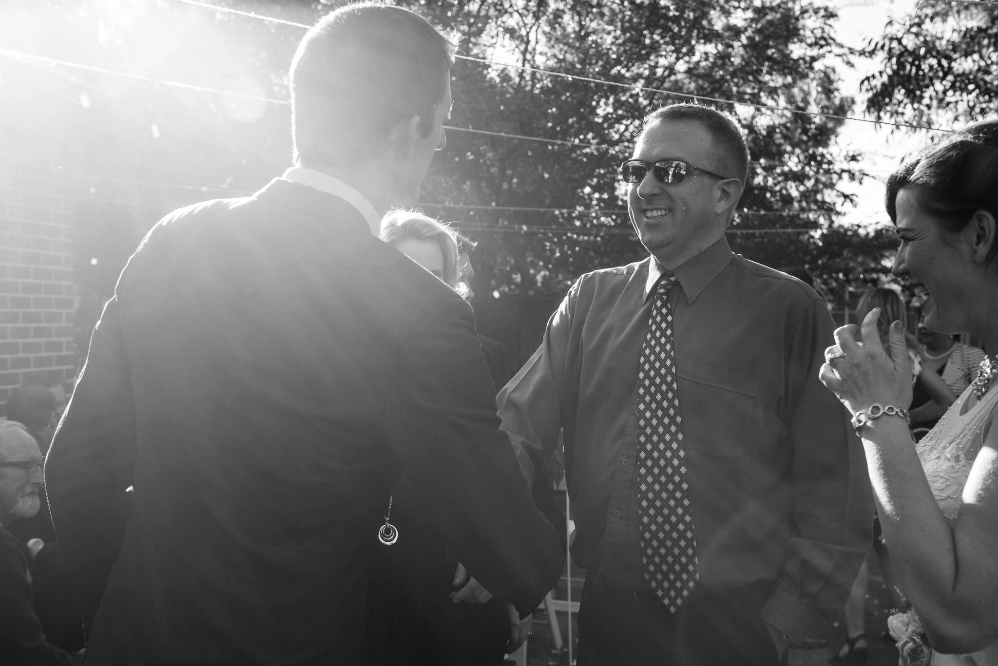 shaking groom's hand with sunflare