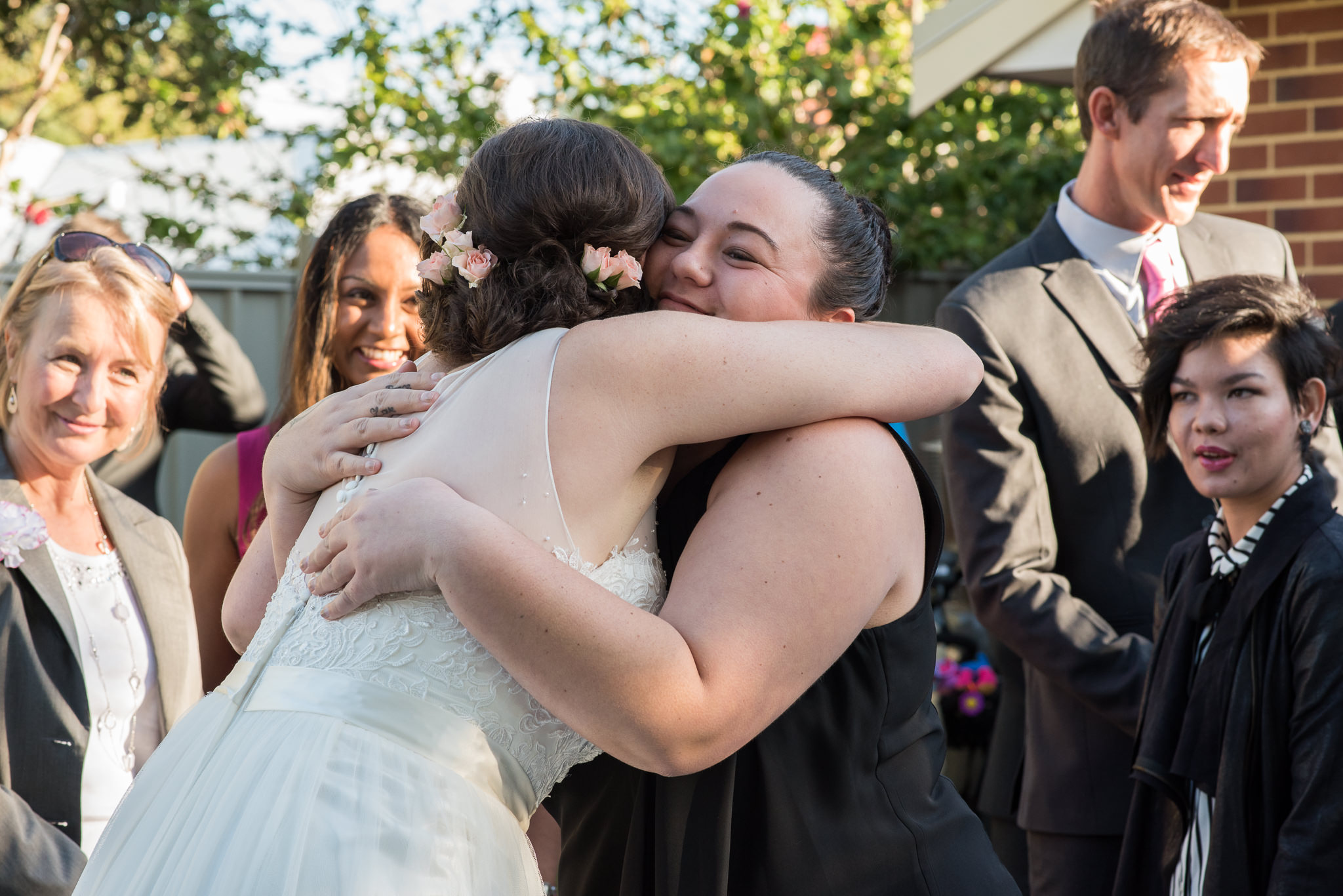 wedding guests hugging bride