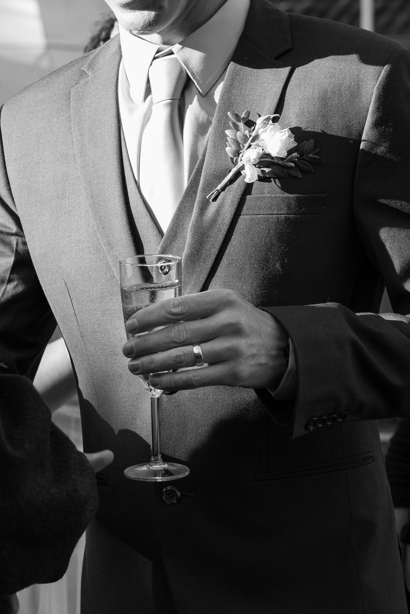 groom holding glass of champagne in afternoon sun