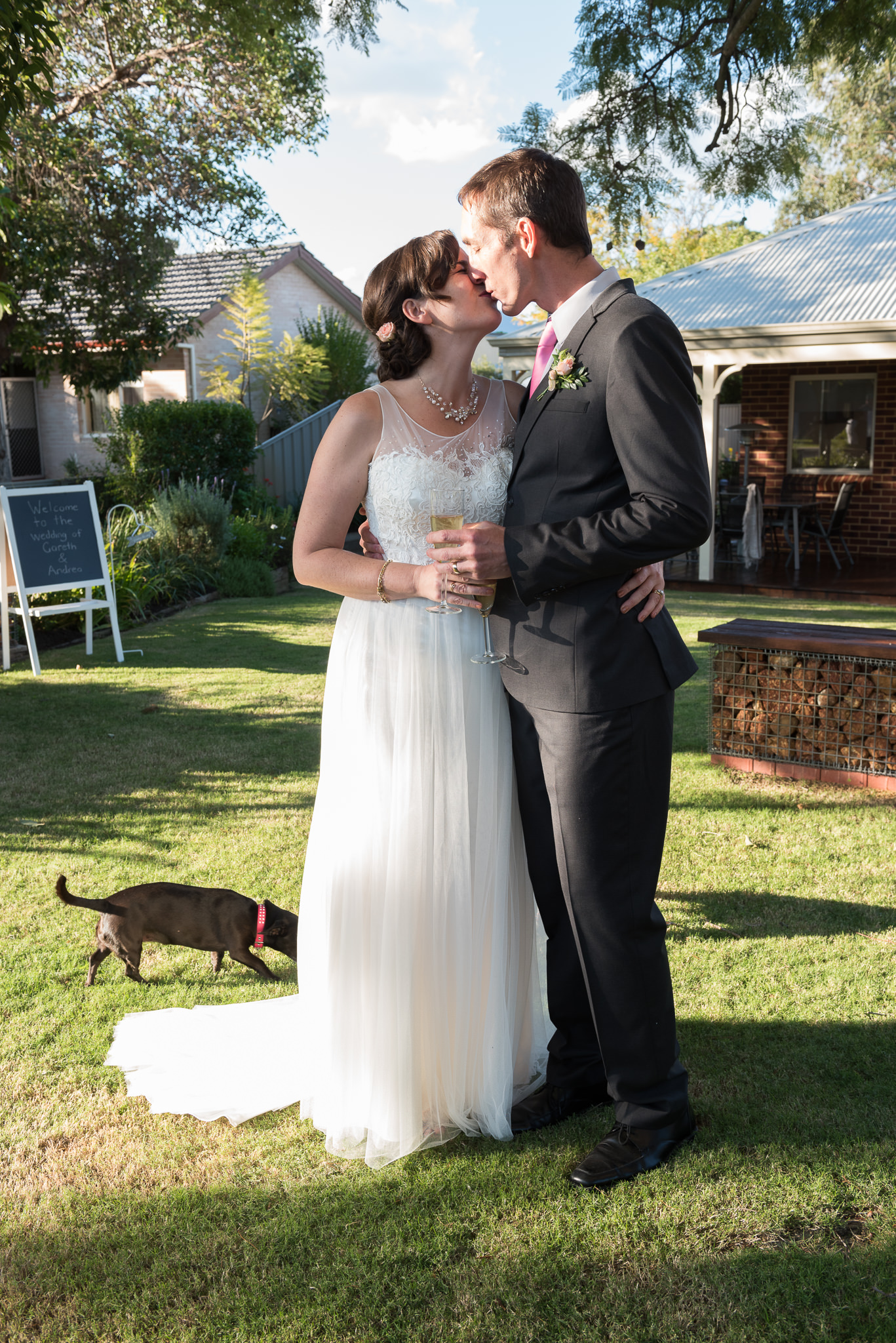 bride and groom kissing in front of family home