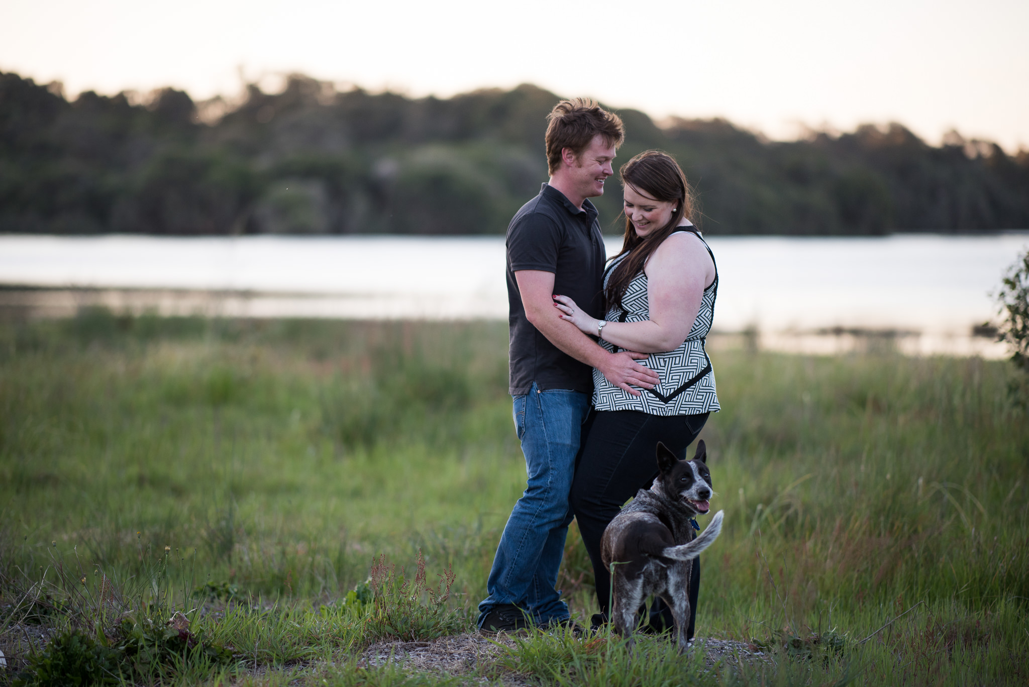 engaged couple with their dog looking at the camera at yellagonga park perth