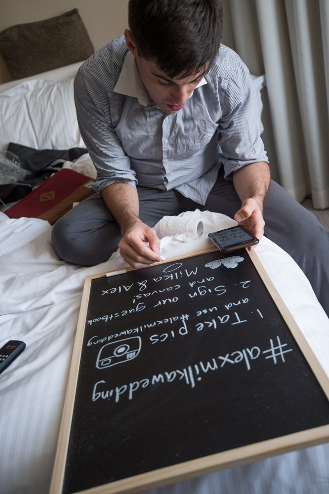 Groomsman writing the hashtag welcome sign for the reception