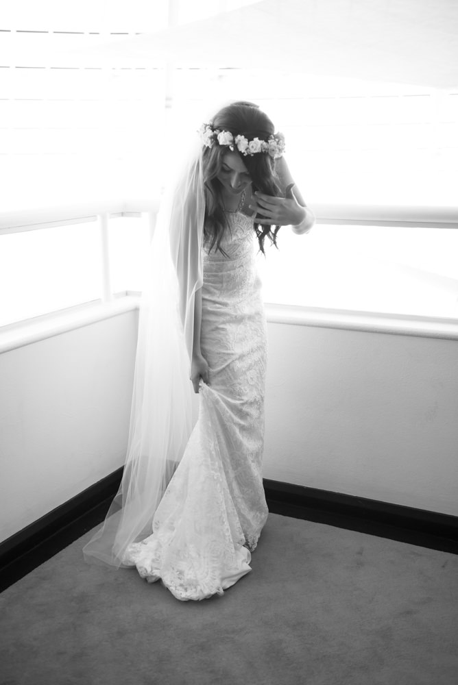 Black and white photo of bride elegantly picking up dress, elegant pose