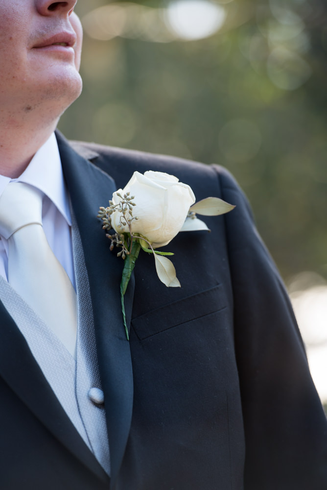 Close-up of the groom's button hole white rose