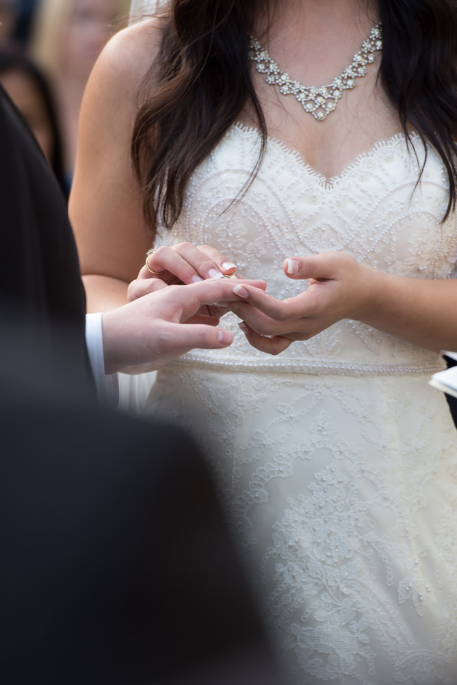 Close up of bride putting the ring on the groom's finger