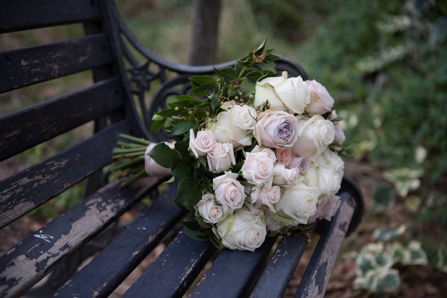 Close-up of Brides bouquet of pastel roses on a rustic bench