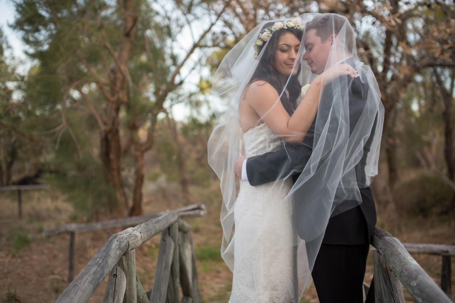 Romantic bride and groom cuddling under bride's veil