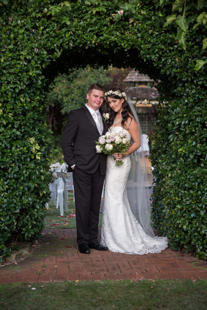 Bride and groom standing in rose archway at Bridgeleigh Reception Centre