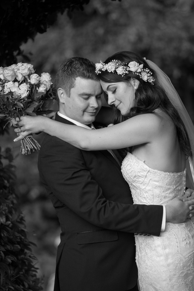 Bride and groom romantic pose with eyes closed, black and white