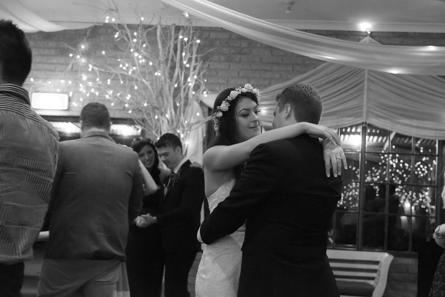 Bride and groom looking at each other while dancing black and white