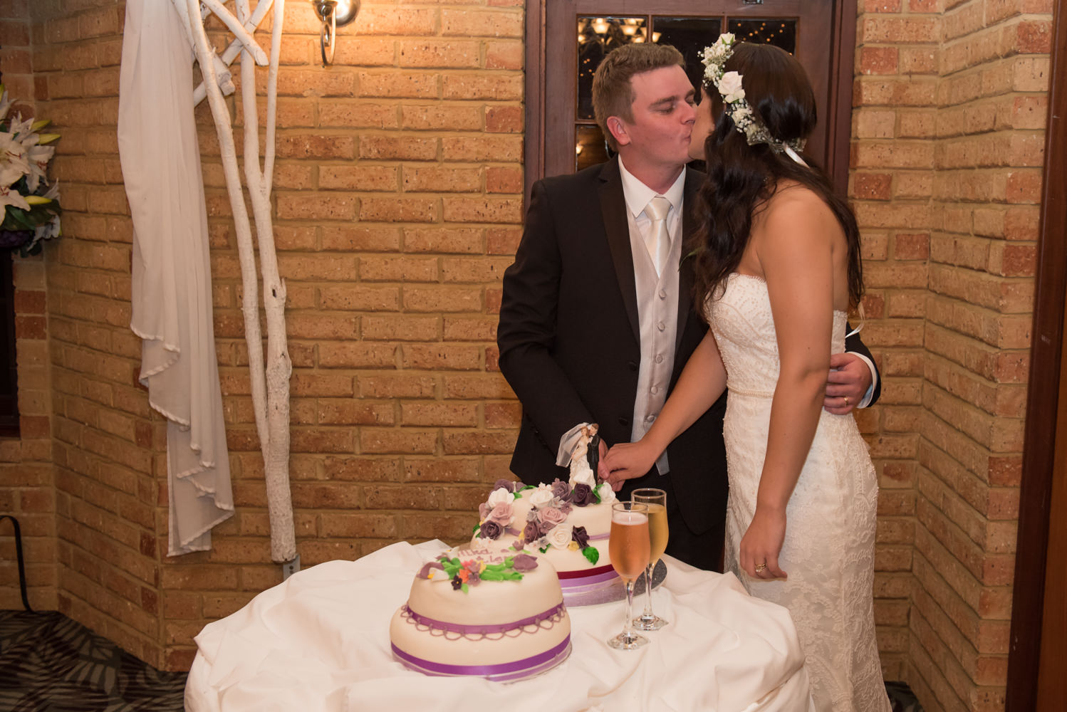 Bride and groom kissing while they cut the cake at Bridgeleigh reception centre