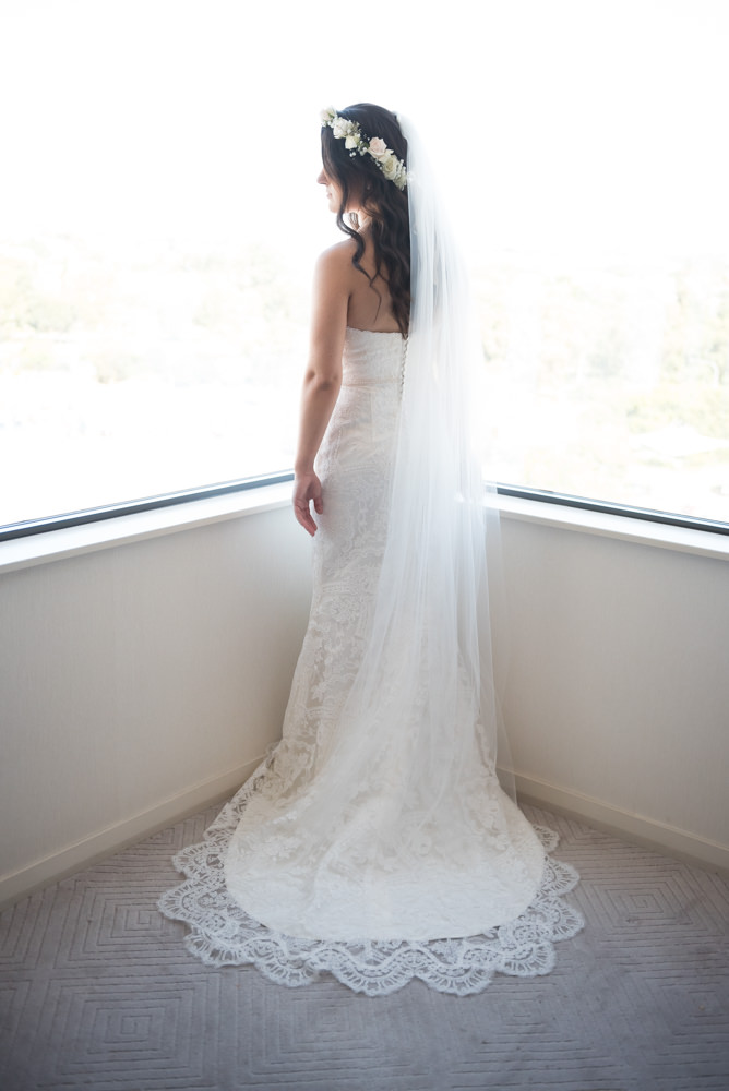 Full length portrait of bride with dress and veil fanned out, lace detail