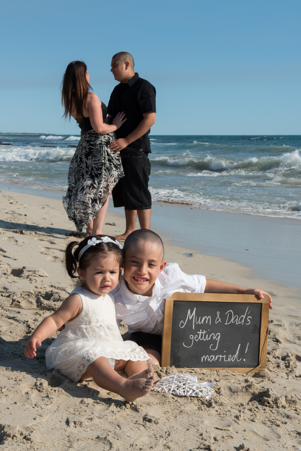 little kids carrying a mum and dad's getting married sign