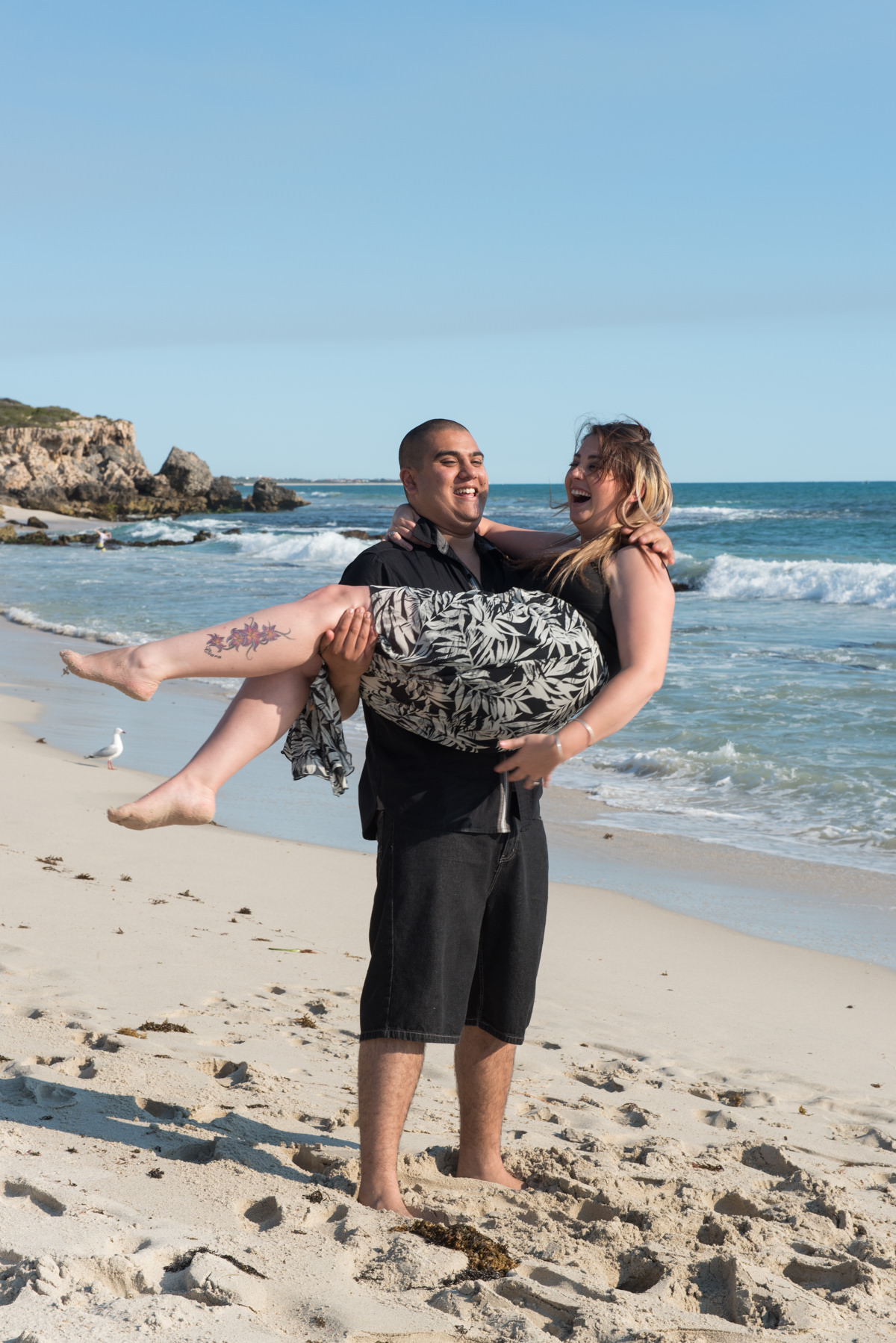 guy swings his fiance around on the sand