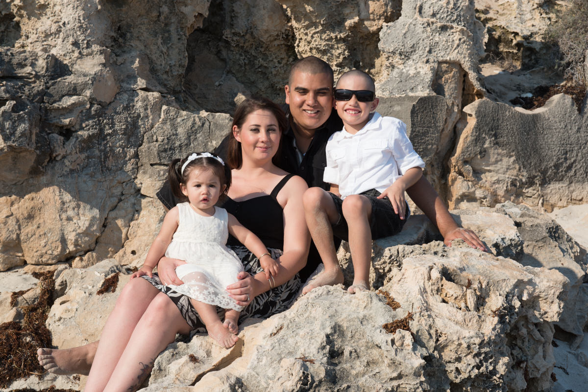 family photo sitting on beach rocks