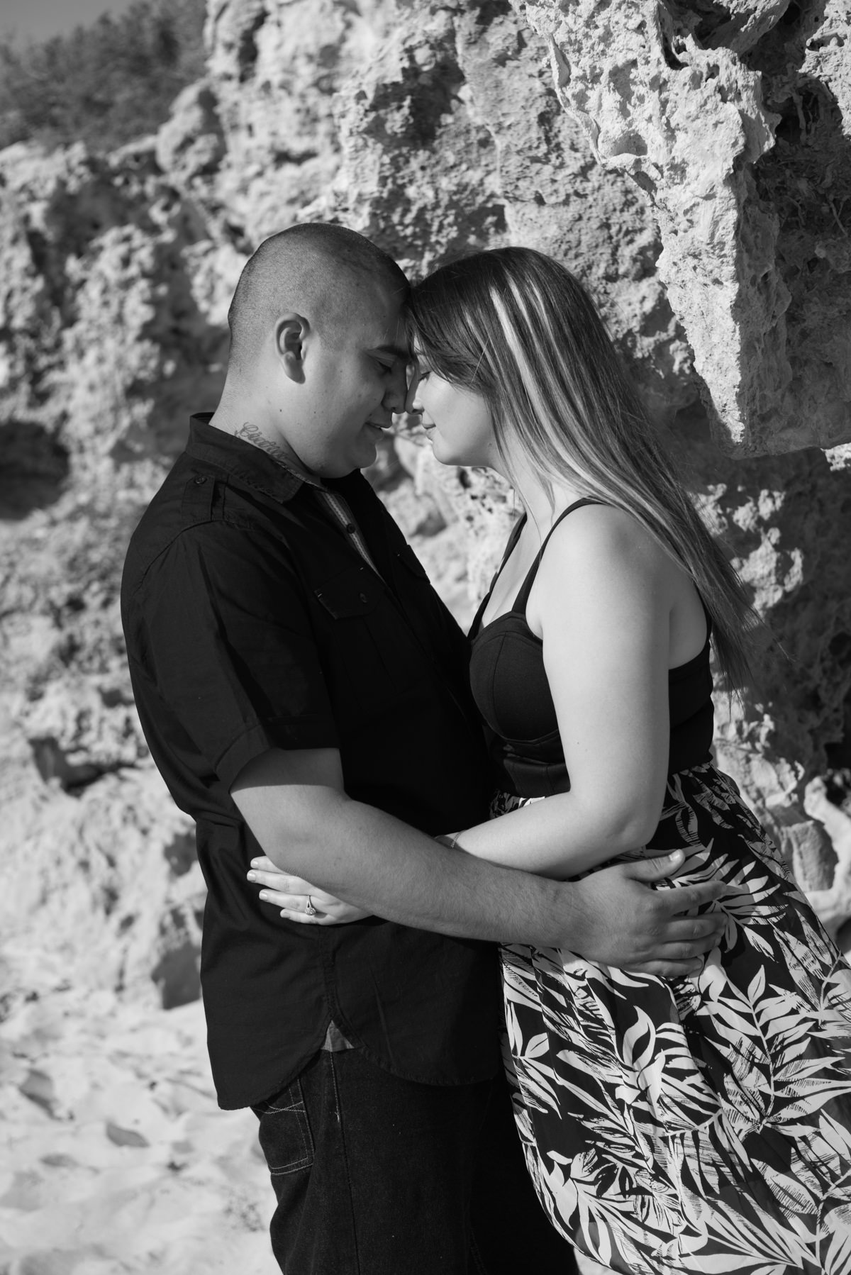 girl and boy cuddling against beach rocks