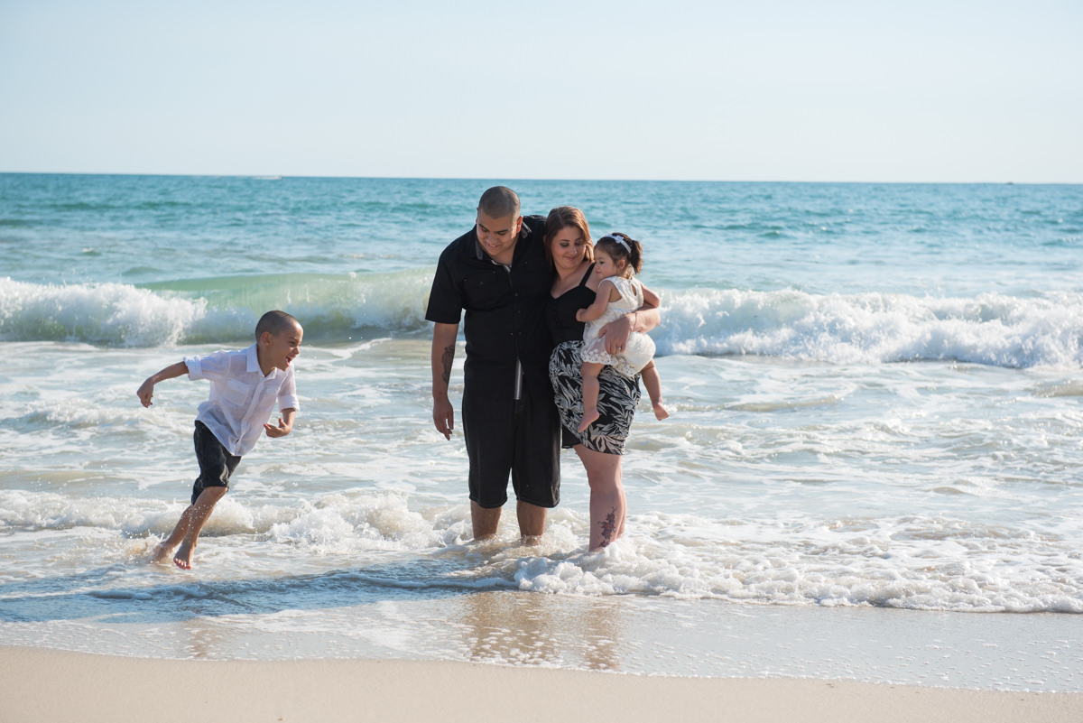 boy runs around his family in the ocean