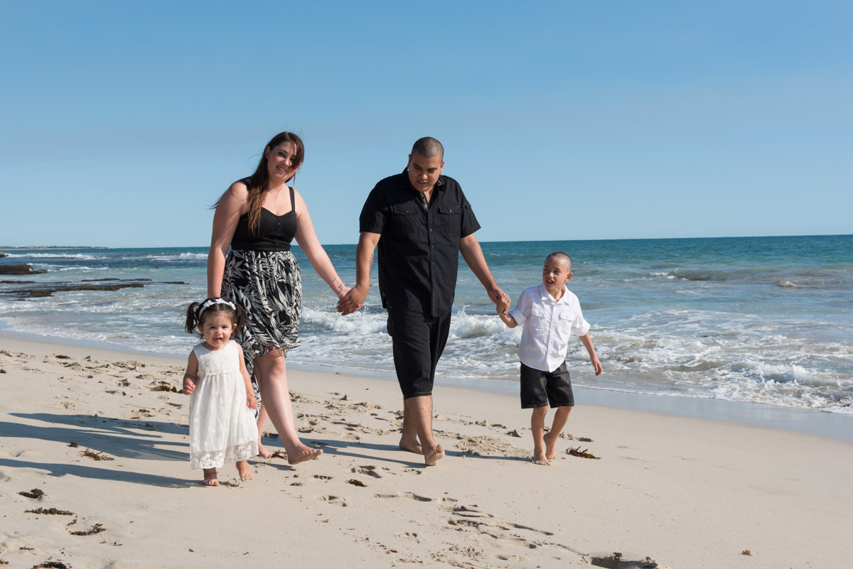 little girl smiles with her family on the beach