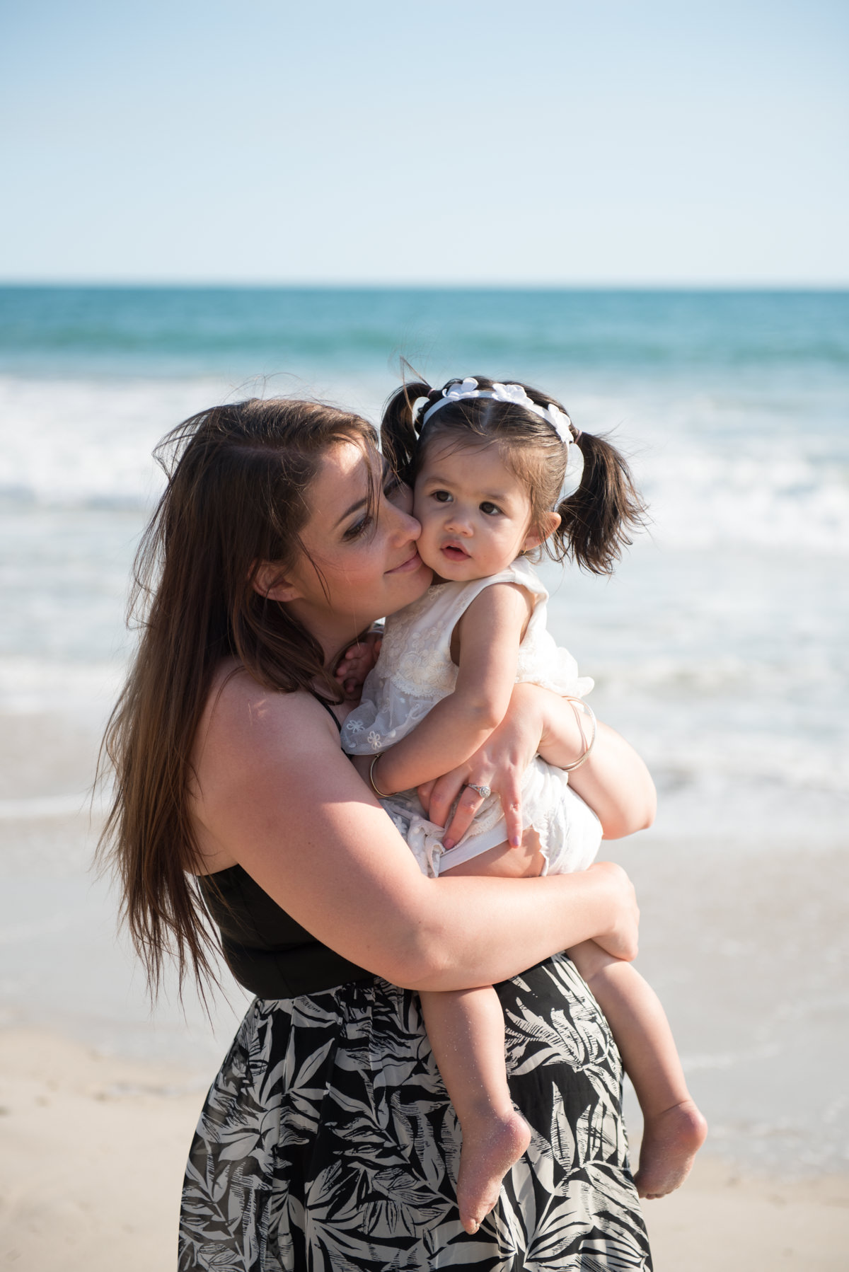 mum snuggling into her young daughter in her arms at Burns Beach