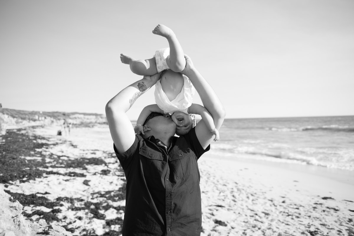 Father kisses his little daughter while he swings her over his head