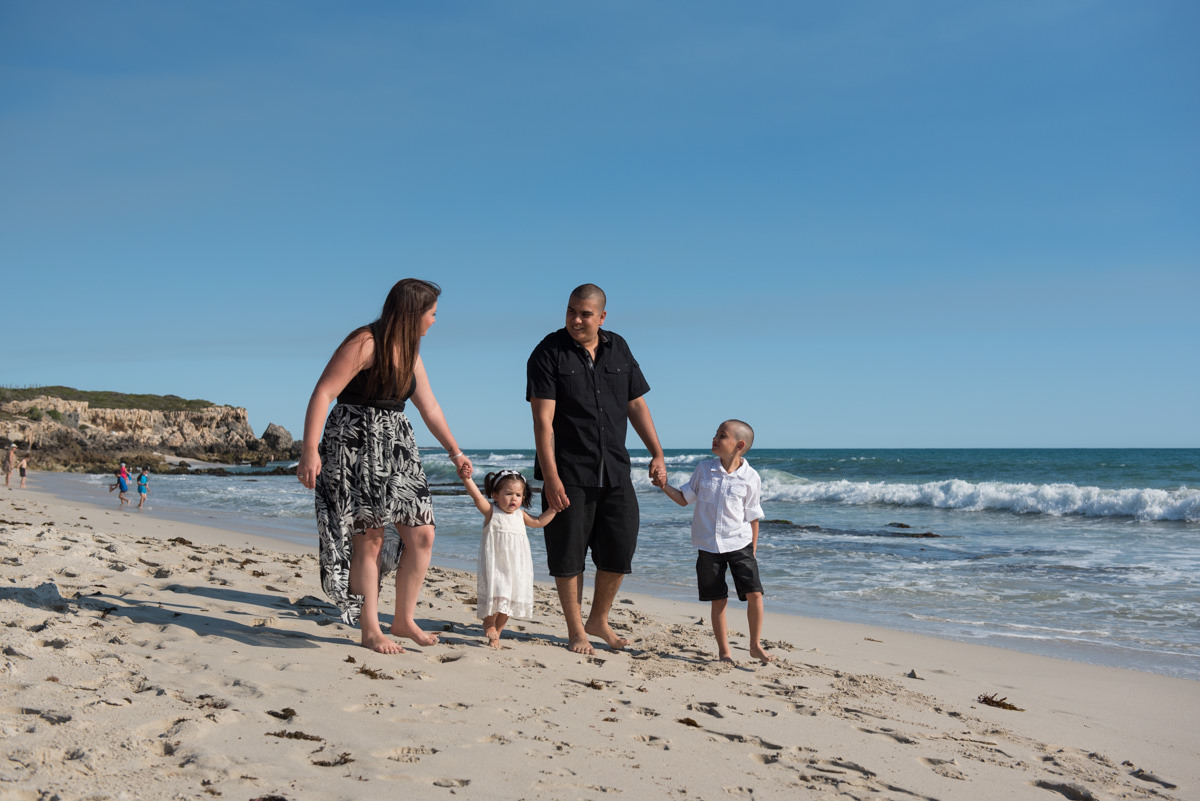 young family walk along Burns beach together