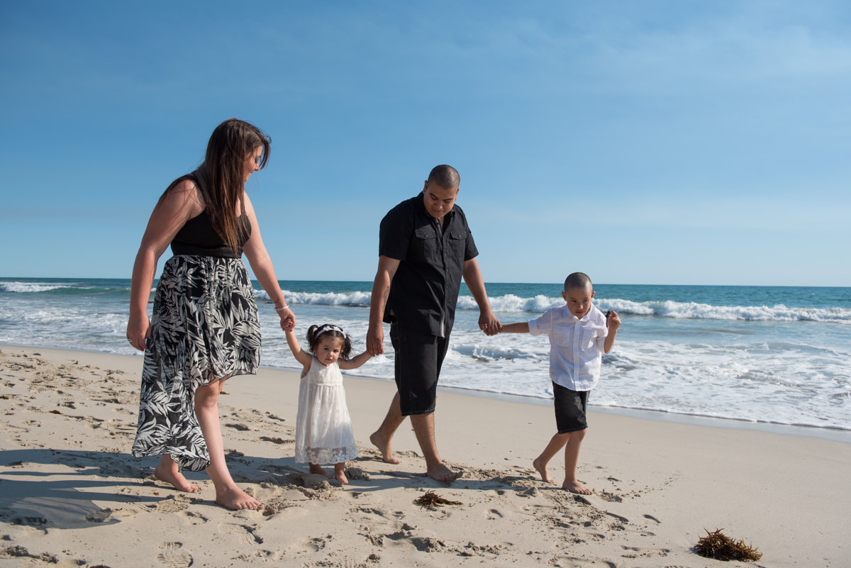 family holding hands and walking along the beach