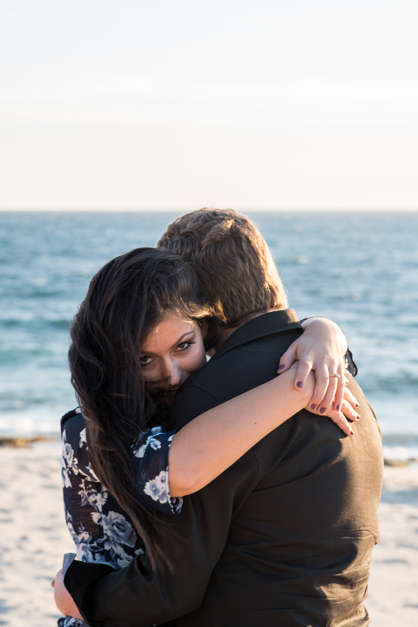 Girl's eyes looking at camera over the shoulder of a boy, hugging