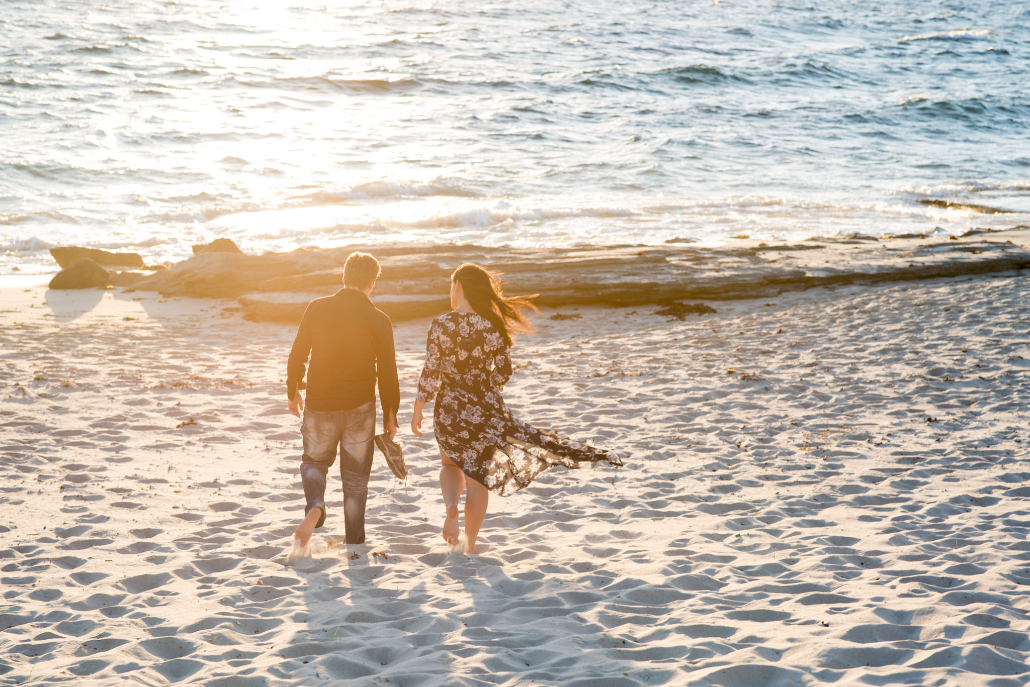 Boy and girl walking towards the sea at golden hour